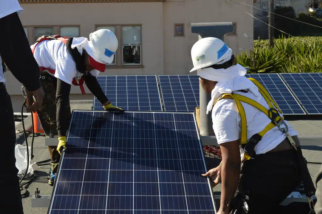 Two women from the YCD job training cohort align a solar panel on the roof of a San Francisco residence.