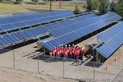 An enormous community solar field with a group of Wells Fargo volunteers in front