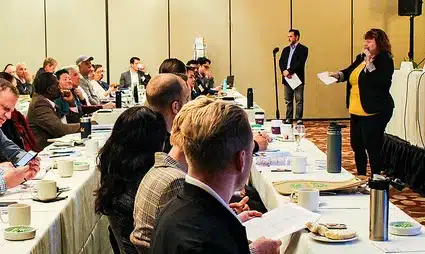 Business conference attendees seated at dining tables during a presentation event