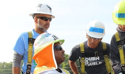 Four construction workers in hard hats and safety vests consulting together outdoors
