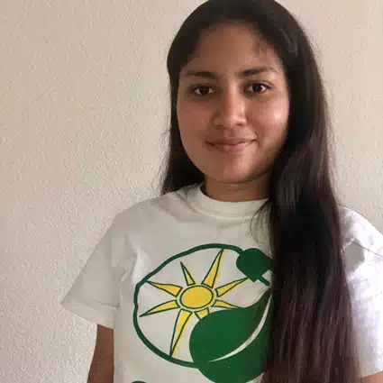 Girl wearing white t-shirt with green and yellow sun logo design