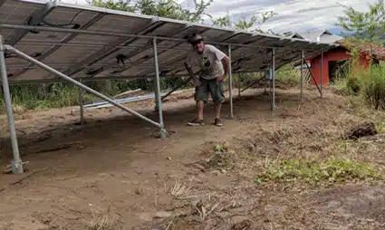 Person working under solar panel structure at rural farm site