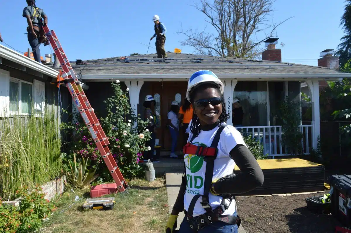 Volunteer in safety gear smiling at camera during home roof repair project