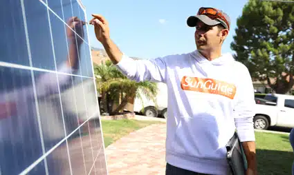 Technician installing solar panel wearing SunCulture branded shirt