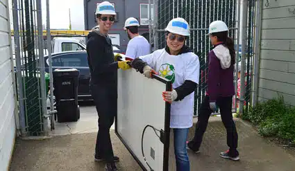 Two volunteers from the CPUC carry a solar panel.