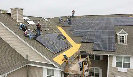 Workers install solar on the roof of the Fair Street apartments.