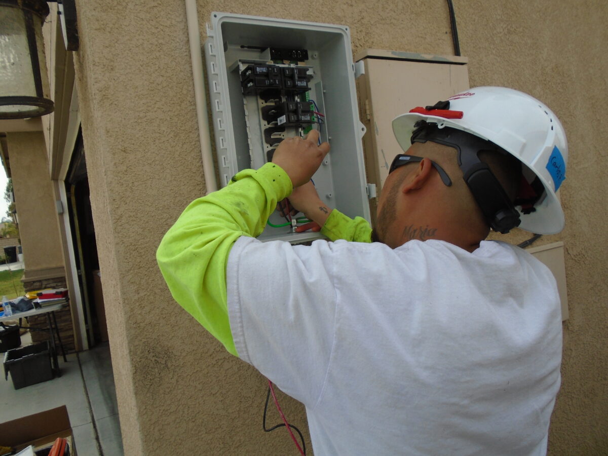Electrician in safety gear working on electrical panel installation