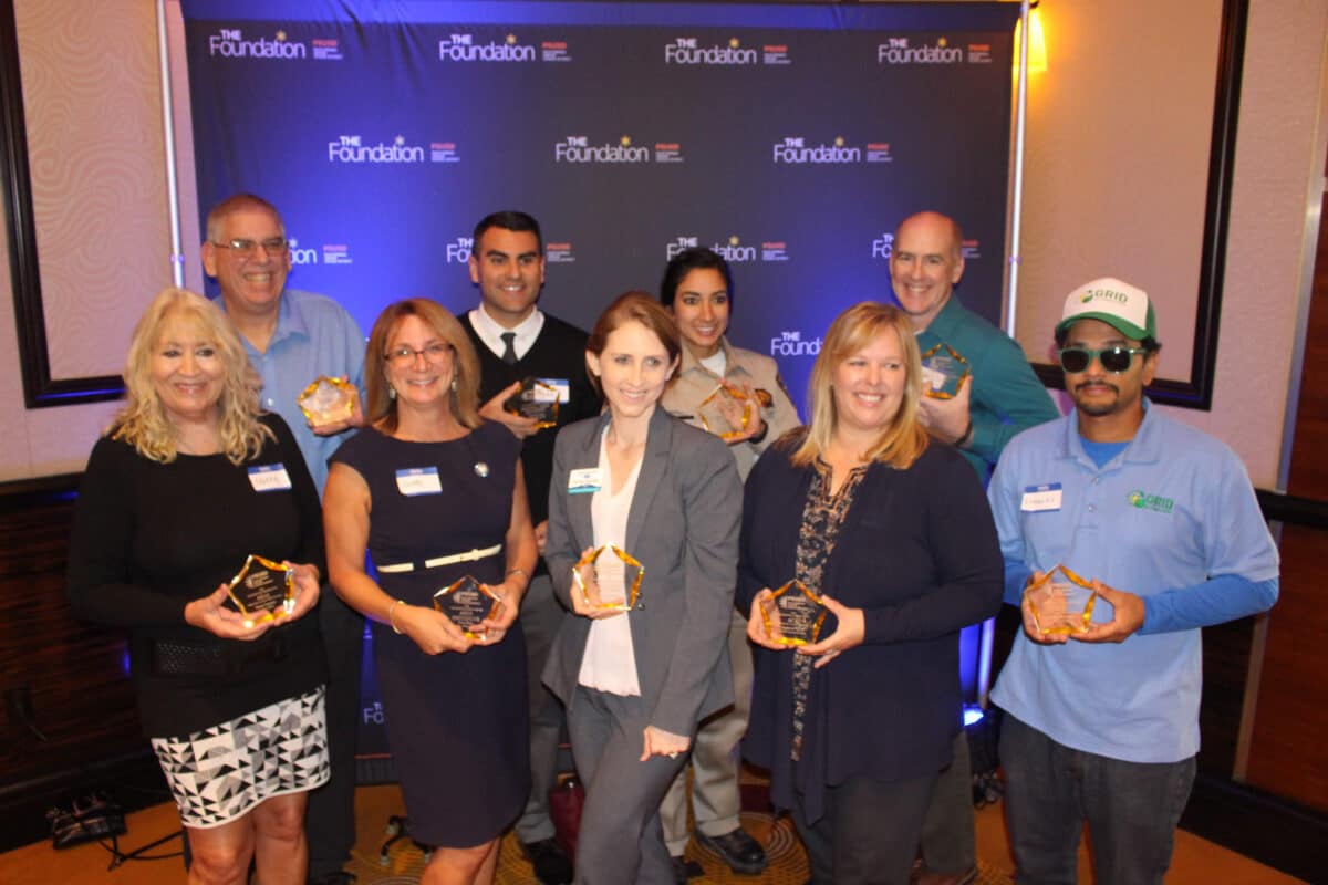 Ten people holding awards at The Foundation Champions of Excellence Awards event