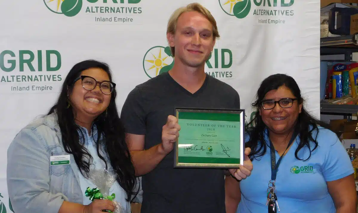 Man holding 2018 Volunteer of the Year award with two women at GRID Alternatives event