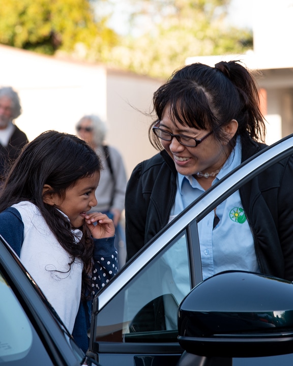Adult and child smiling by car