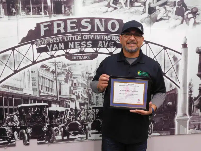 Man holding award certificate in front of Fresno Van Ness Ave vintage mural