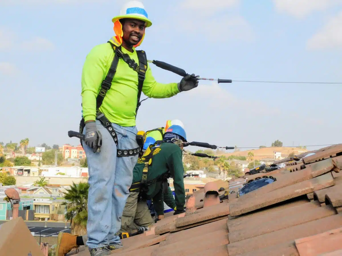 Worker in safety gear on rooftop instructing child on zip line course