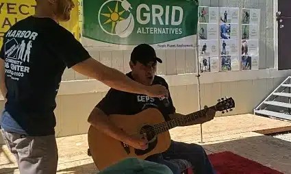 Man playing acoustic guitar outdoors at GRID Alternatives event