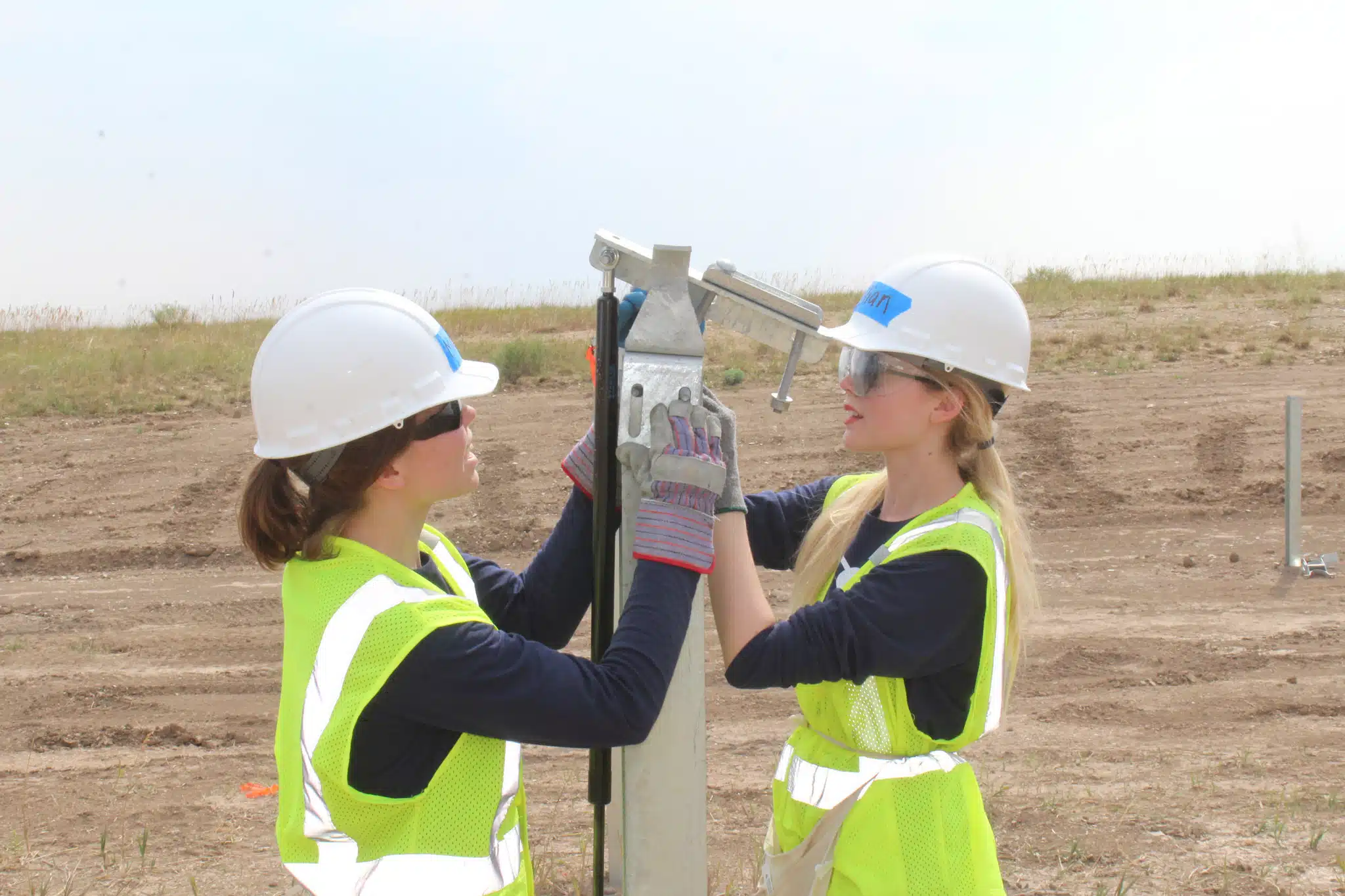 Gillian (right) works with a partner to place a dampener bracket on top of a large post.