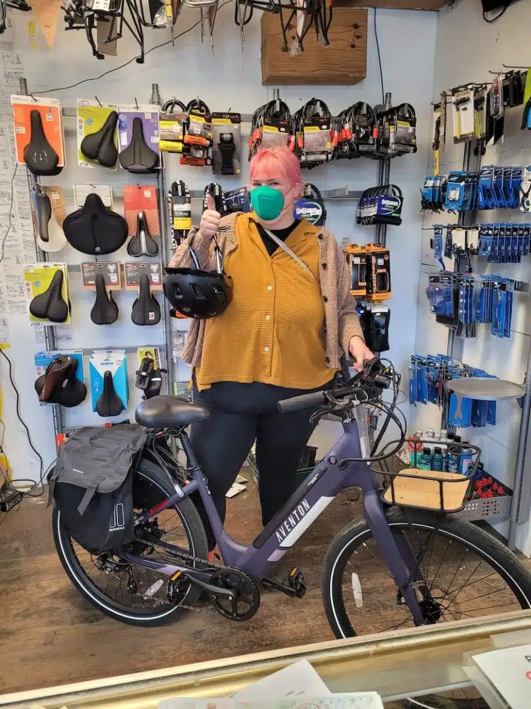 An Electric Bike program beneficiary stands next to her new E-bike at the Watershed Workshop, a community based organization that has partnered up with GRID Alternatives Bay Area's Clean Mobility Program