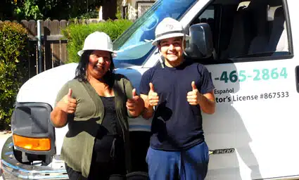 Two workers in hard hats giving thumbs up in front of service vehicle with license number 867533