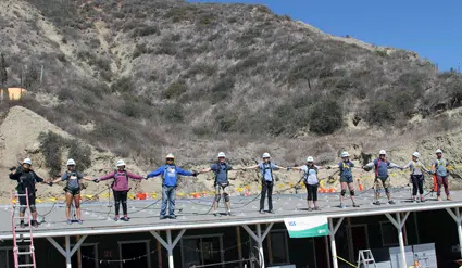 Group of people standing on a platform with a hillside background during an event