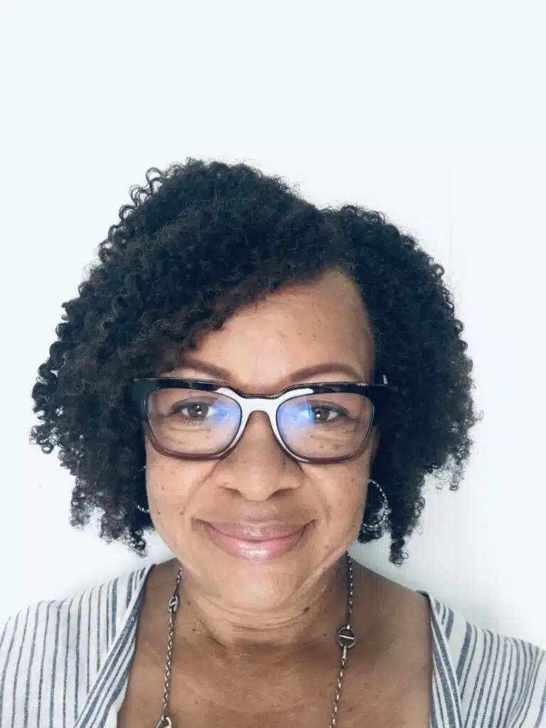 A person with curly dark hair and glasses smiles in a profile picture