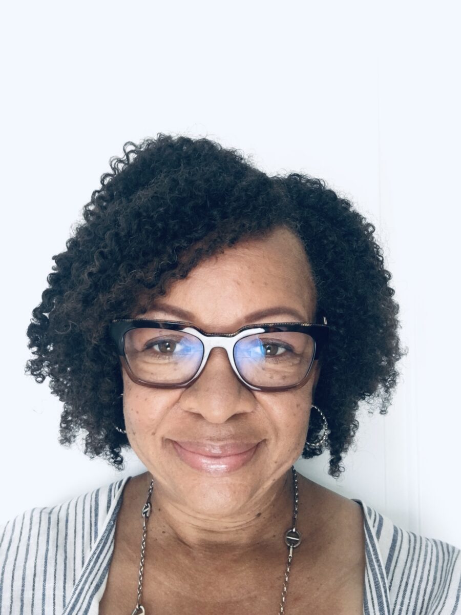 A person with curly dark hair and glasses smiles in a profile picture