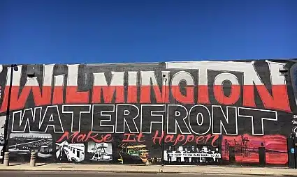 Wilmington Waterfront mural with red and black lettering on white building wall