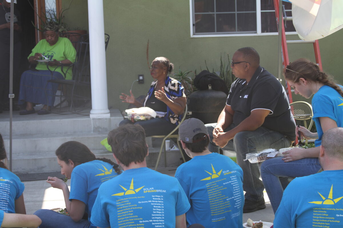 Group of people wearing blue Solar Springbreak t-shirts seated outdoors listening to speakers at an event