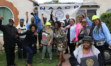 Group of people celebrating in front of NAACP banner outdoors