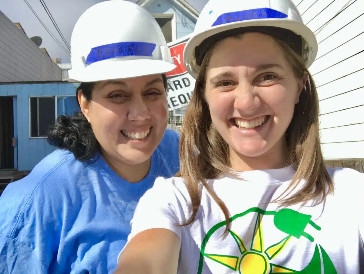 Dolores Garay and Lauren Morgan take a selfie while wearing hard hats at a GRID install
