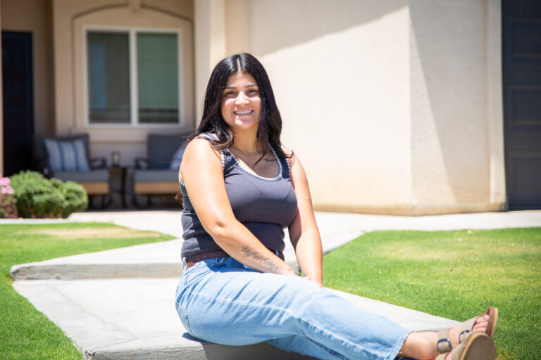 Woman sitting down in front of her home