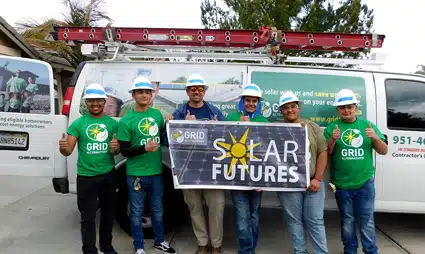 Six people in green GRID shirts holding a "Solar Futures" banner in front of a work van