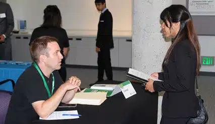 A job fair attendee speaks with an employer about opportunities during the Bay Area Summer Job Fair.