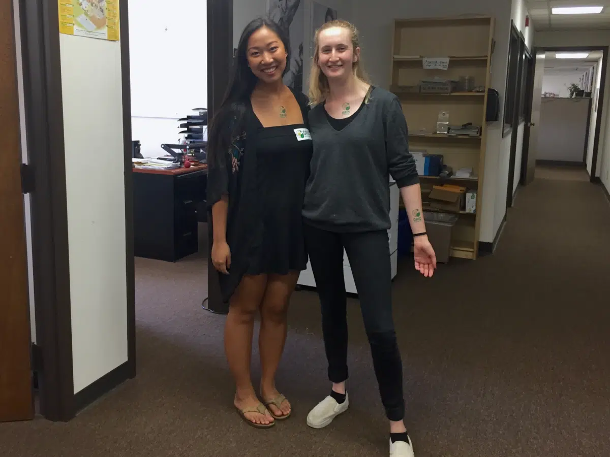 Two smiling women posing together in an office hallway
