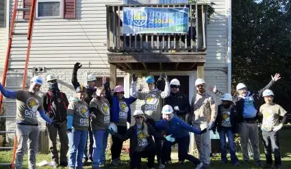 KPMG Veteran volunteers pose in front of a Troops to Solar banner