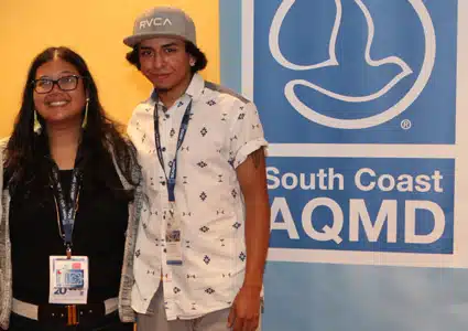 Two people posing together at South Coast AQMD event with lanyard badges