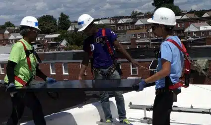 Homeowner Pamela and two volunteers put in a solar panel