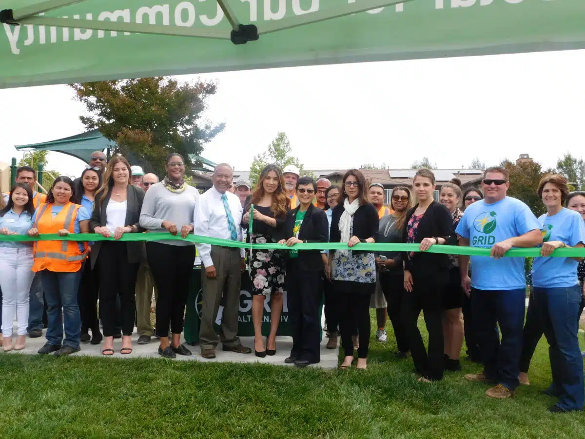 Group of people holding a green ribbon at a Madera Vista ribbon-cutting ceremony