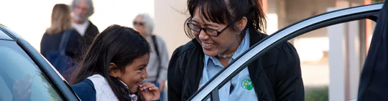 Woman smiles at child exiting an electric vehicle