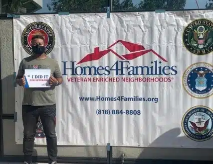 Nick Boateng stands in front of a Homes4Families banner