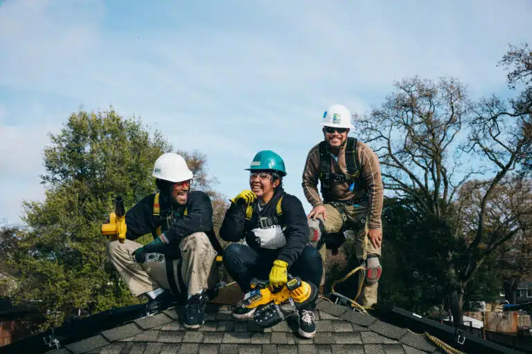 Three construction workers in safety gear posing on a roof