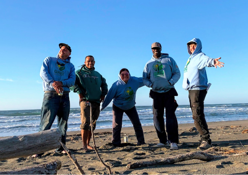GRID Bay Area's North Coast team is standing for a picture in the beach