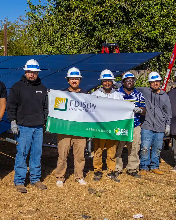 Five construction workers holding Edison International banner at community event