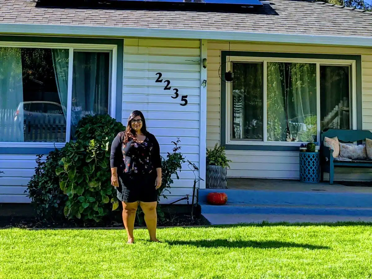 Woman standing on lawn in front of house numbered 2235