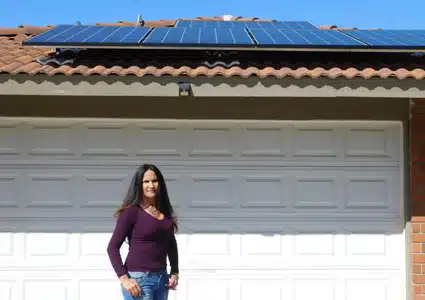 Woman standing in front of house with solar panels on roof