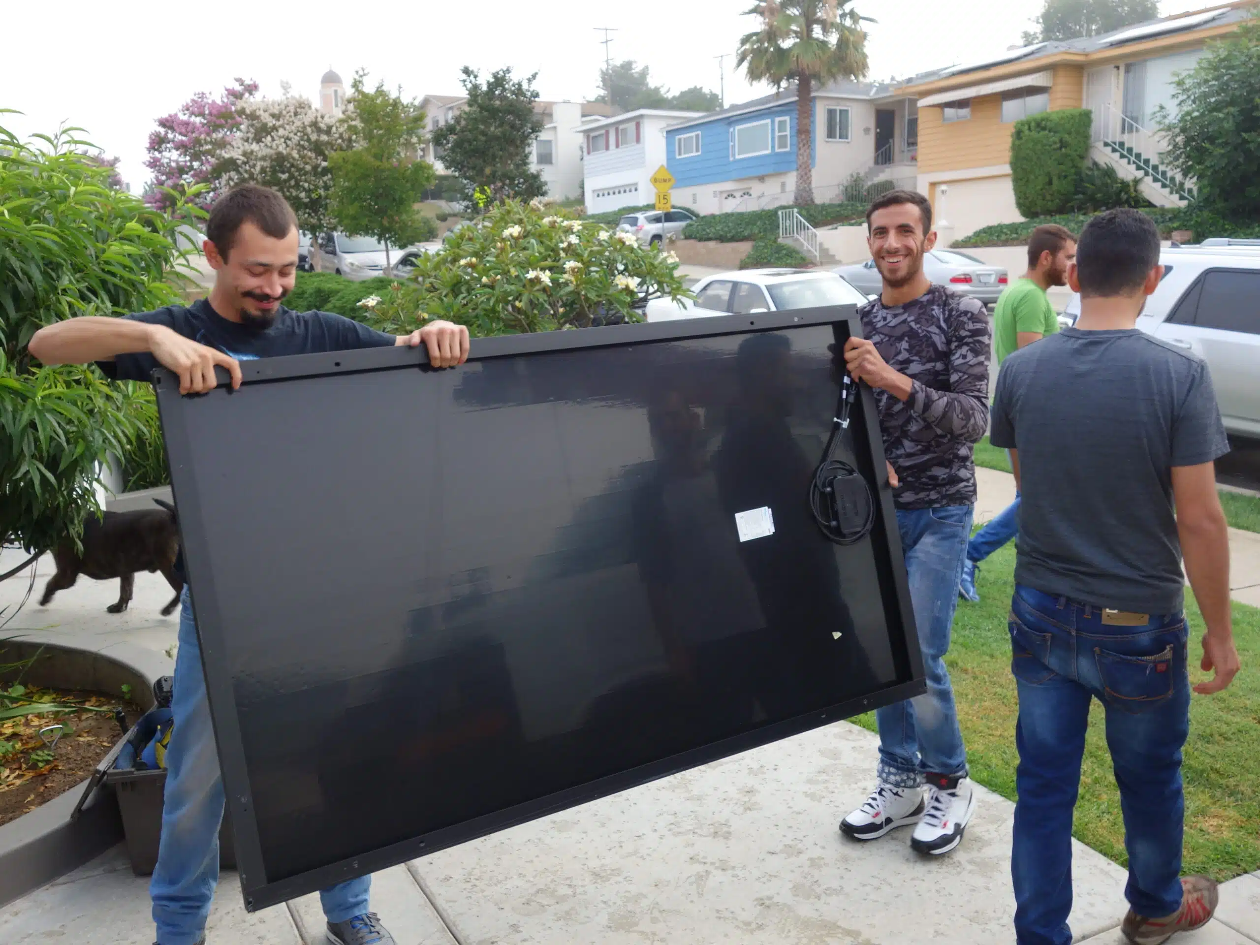 Three refugee volunteers unload solar panels from a GRID van.