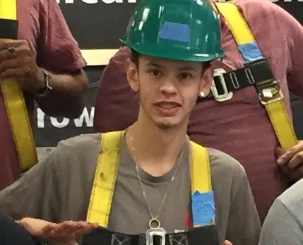 Young man wearing green hard hat and yellow safety vest at construction or trade event