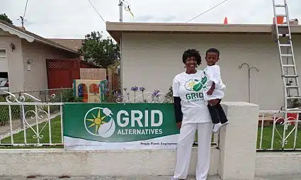 Woman and child holding young boy in front of GRID Alternatives banner at residential home