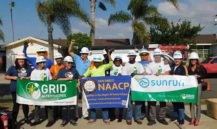 Group of construction workers holding GRID Alternatives, NAACP, and SunRun banners at community event