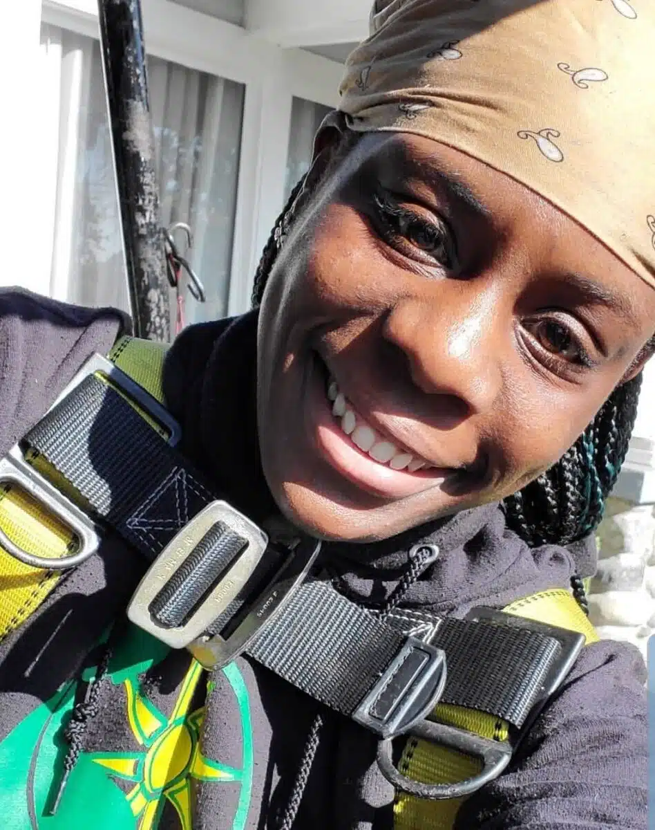 Person wearing black and yellow safety harness smiling at camera indoors
