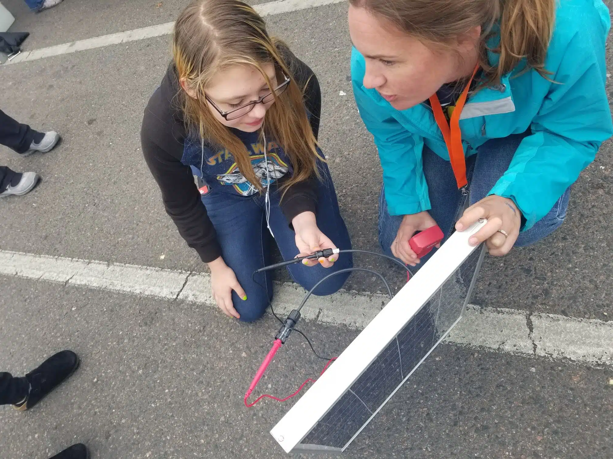 Allison Moe, GRID's Workforce Development Manager, demonstrates solar module testing to a young girl