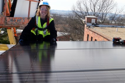 Solar Spring Breaker Abby smiles after installing a solar panel
