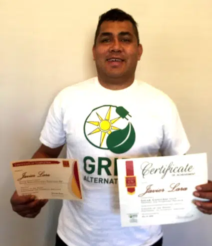Man holding certificates wearing GRID Alternatives shirt with sun and leaf logo